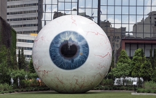 giant eyeball in front of large corporation